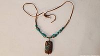 Front view of turquoise necklace showing pendant and beads on leather cord.