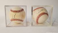 Two autographed baseballs together, each in separate clear display cases