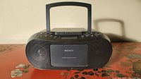 Front view of vintage black Sony boombox showing speaker grills, central CD compartment, and handle.