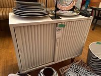 Front view of white cabinet with sliding doors and items on top