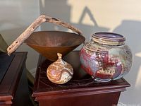 Overview of copper bowl with driftwood handle, glazed pottery jar, small container