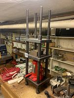 Full view of the hydraulic press setup on a workbench showing the frame, bottle jack, and threaded rods.