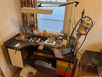 Jewelry bench desk top showing Foredom rotary tool, lamp, trays, chisels and small containers