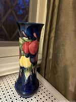 Full side view showing tall trumpet shape and fruit motif