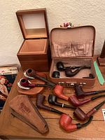 Eight assorted tobacco pipes and accessories laid out on wooden table