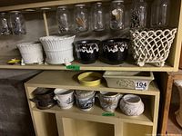 Top shelf showing two white fluted planters, two black drip-glazed pots, white lattice basket planter