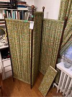 Full view of assembled three-panel privacy screen with extra fabric bolt on floor