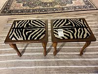 Pair of wooden stools on striped rug, top view of zebra upholstery