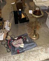Photo showing the standing ashtray and the Royal hand vacuum on the floor in a garage environment with other items in the background.