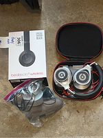 Beats Solo 3 wireless headphones in carrying case next to original special edition black box, with second pair of Beats headphones in plastic bag.