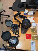 Top view showing multiple lenses, filters in boxes, camera handles, and cases arranged on table.