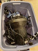 Blue tote containing the American DJ Millennium YB1 black dome lighting unit with attached cords and mounting bracket.