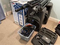 Two Mackie active speakers with stacked tripod stands, plastic bin of cables, and carrying case with accessories