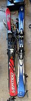 Pair of Volkl and K2 downhill skis side by side showing bindings and colors
