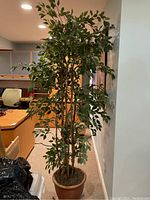Full view of the artificial plant showing height, foliage, and pot placement in an office or room environment.