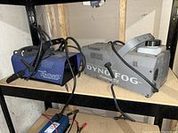 Dyno-Fog and Shadow II fog machines side by side on shelf with power cords visible