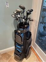 Full view of golf bag with clubs inside, showing multiple clubs with worn metal heads and graphite shafts.
