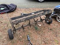 Side angle view showing plug aerator tines and tires on patchy ground with vehicle tire nearby