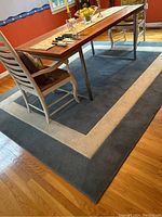Overall image of the blue and cream area rug under a dining table with chairs on hardwood floor.