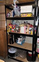 Full view of metal shelving unit loaded with various household items showing the black metal frame and pressed board shelves.
