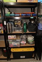 Full view of black metal shelving unit with pressed wood shelves and various storage items on shelves.