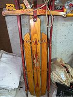 Full view of the vintage sled showing wooden slats with painted arrows and illustration, red metal frame, and Flexible Flyer branding.