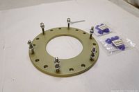 Circular steel anchor plate with mounted bolts and nuts on white background, showing condition and hardware.