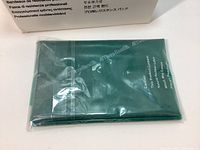 Green flat latex resistance band folded and sealed in plastic wrap, showing material texture and branding.