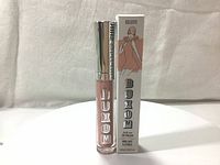 Front view of Buxom lip gloss tube next to original box showing product and branding