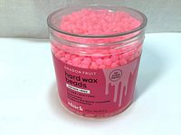 Jar of pink Sliick Dragon Fruit scented infused hard wax beads for waxing face and body, with label showing product details.