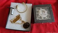 Photo showing gold-tone chain bangle with a dark brown rounded pendant necklace and a black box with a gold-tone bangle inside.