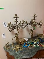Pair of brass candelabras alongside small bells and door knocker on tabletop