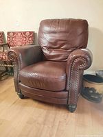 Front view of brown leather armchair on hardwood floor