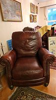 Front view of brown leather chair with rolled arms and nailhead trim