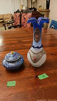 Photo of both the cloisonne bowl with lid and the vintage ruffled rim vase placed on a wooden table.