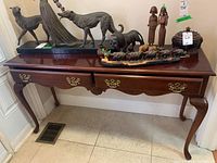 Full view of wood console table with two drawers, brass handles, and various decorative items on top (not included). Shows overall condition and style.