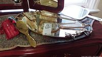 Dresser items including two hairbrushes, brushes, and the mirrored tray with decorative handles and floral motifs