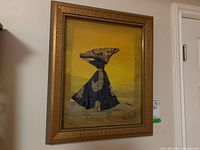 Full front view of the framed fabric art figure against a yellow background with ornate gold frame.