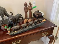 Lot displayed on wooden furniture surface showing lion, oxen with cart, small animals, tall female figurines, and trinket boxes.