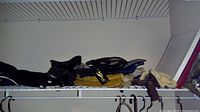 Gloves in various colors and materials laid on a white wire shelf, including black and tan leather gloves and fur-lined gloves