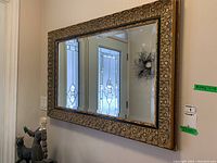 Wide view of mirror hung on wall reflecting front door and entryway