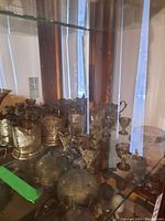 Display case view of multiple silver filigree holders and small dishes