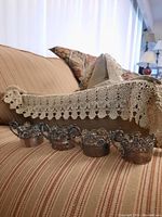 Five silver-plated filigree egg holders mounted on a horizontal rack, ornate scrollwork