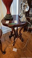 Side angled view of the vintage wood table showing ornate legs and shaped top with items on top (not included)