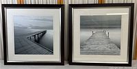 Both framed photo prints side by side showing ocean piers in black and white, depicting serene water and sky scenes with wooden piers.