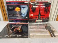 Four sealed LaserDiscs lying flat showing their front covers, including Waterworld, Crimson Tide, Dances with Wolves, and another with a man in suit.