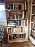 Overview of wooden bookshelf with five shelves filled with hardcover books of various sizes and colors.