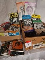 Two boxes filled with multiple Films in Review magazines showing colorful, artistic covers with film-related imagery.