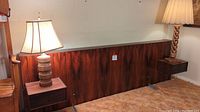 Full view of wood veneer headboard with two floating nightstands and two table lamps