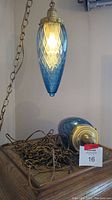 Lamp and detached shade on wooden surface with coiled chain and wiring, auction tag visible
